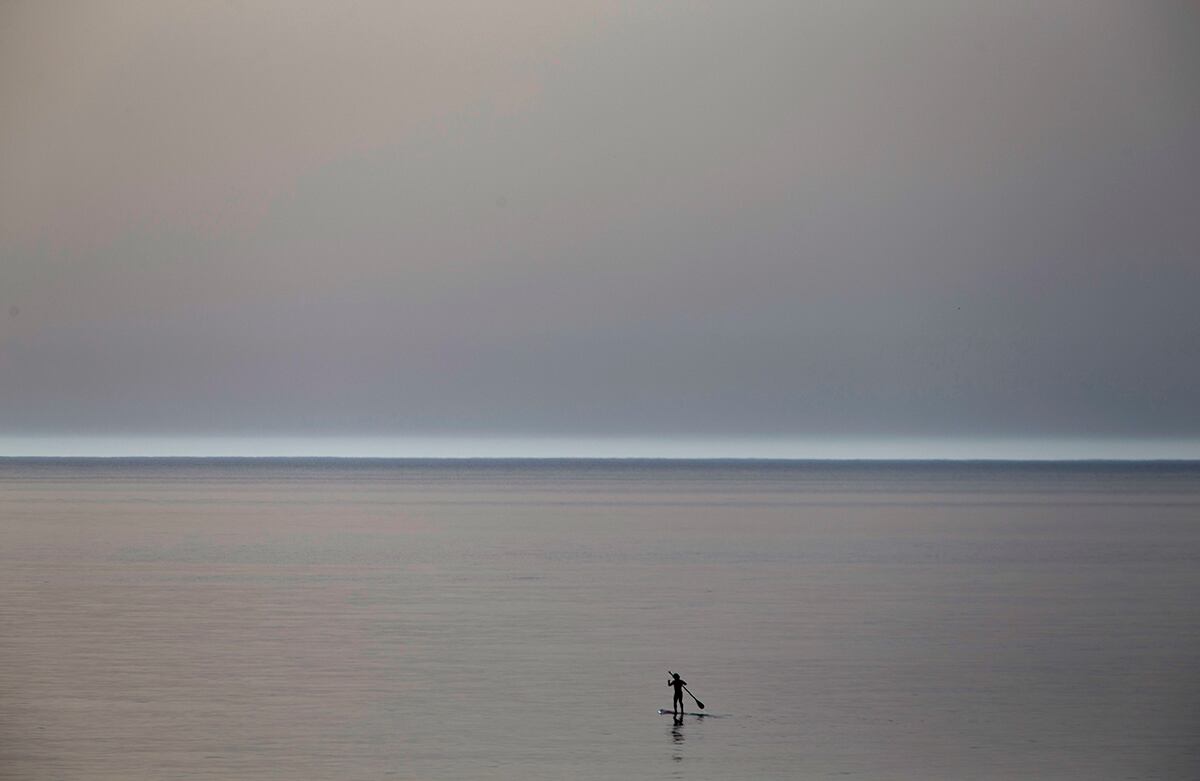 Un surfista rema en el tranquilo y silencioso mar Mediterráneo cerca a la comunidad de Beit Yanai, Israel. (AP)
