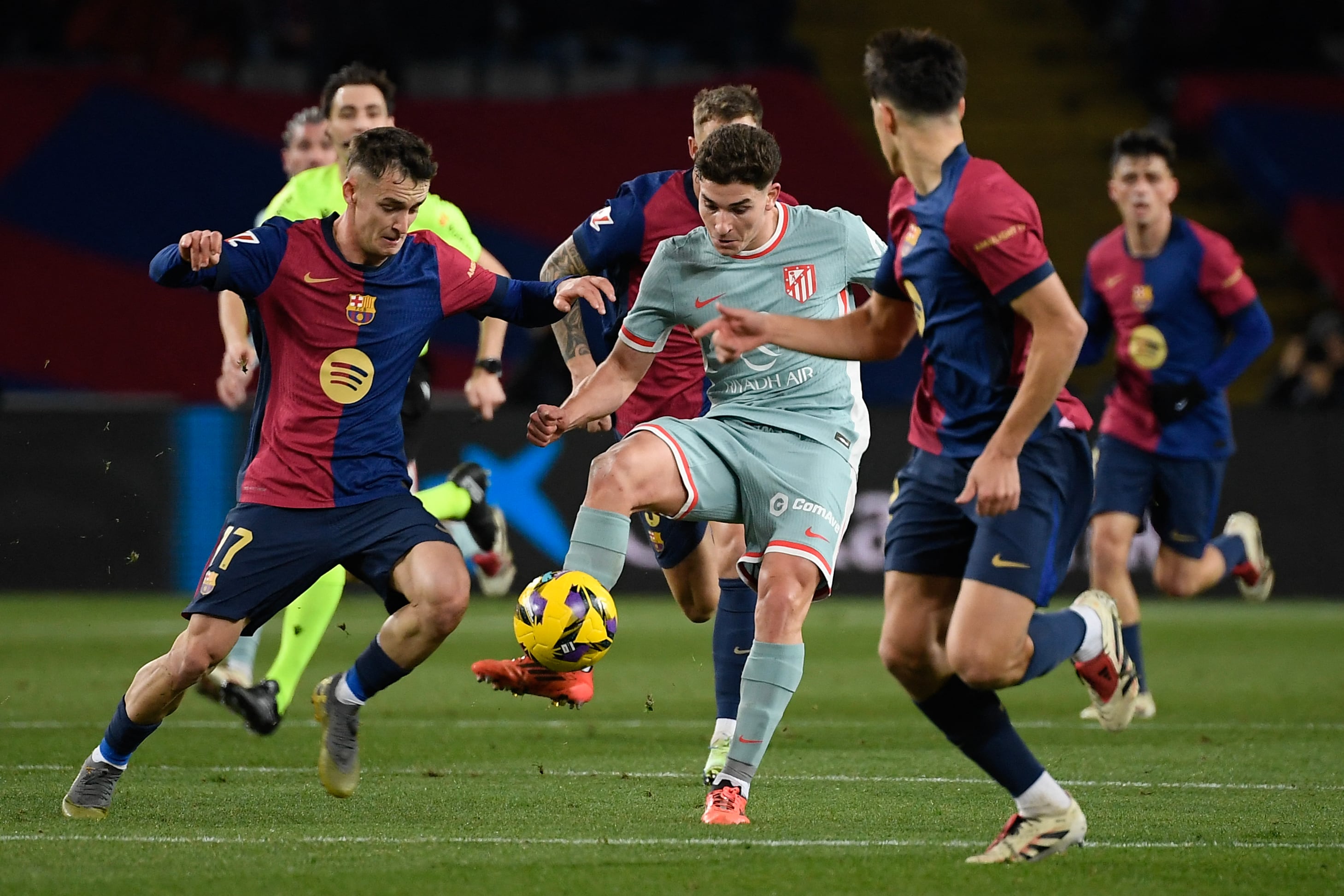El delantero argentino del Atlético de Madrid #19 Julián Álvarez (C) es desafiado por el centrocampista español del Barcelona #17 Marc Casado durante la liga española.