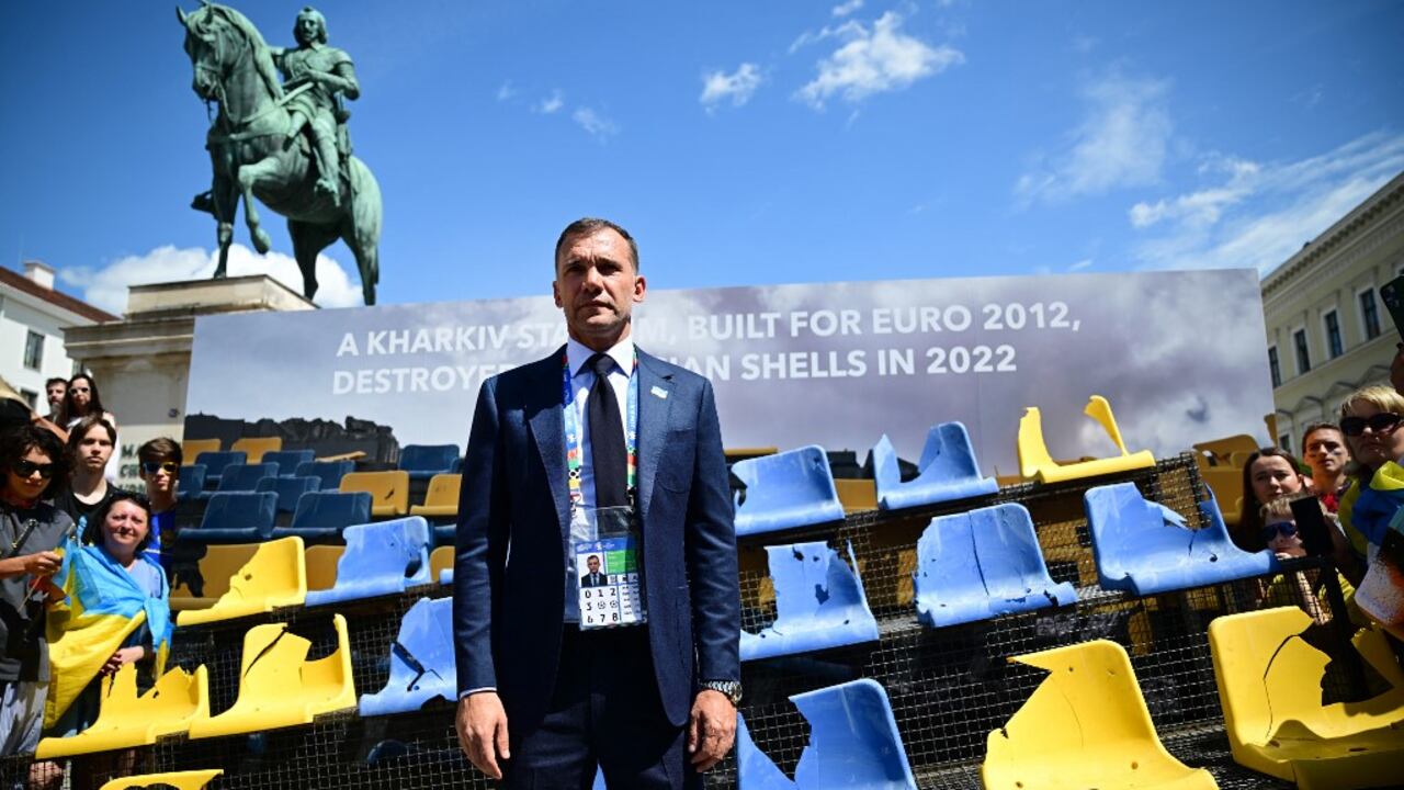 El presidente de la Asociación Ucraniana de Fútbol, Andriy Shevchenko, posa frente a una instalación de asientos dañados con los colores de Ucrania tomada del estadio de fútbol Sonyachny en Kharkiv, Ucrania, el 17 de junio de 2024 en Munich, sur de Alemania. La instalación está dedicada a las instalaciones deportivas que fueron bombardeadas durante la guerra ruso-ucraniana. Járkov fue una de las ciudades que acogió el Campeonato Europeo de Fútbol UEFA Euro 2012. El estadio Sonyachny se construyó para esta competición y posteriormente se utilizó como campo de entrenamiento de la selección nacional de fútbol de Ucrania. Fue destruido por los bombardeos rusos en mayo de 2022. (Foto de Tobias SCHWARZ / AFP)