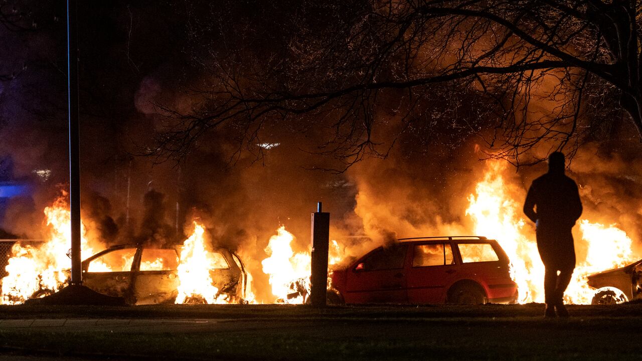 Varios vehículos son arrasados por las llamas tras el estallido de protestas en Rosengard, distrito de Malmö, Suecia. (Johan Nilsson/TT vía AP)