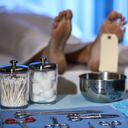 Dead woman's corpse in morgue. Focus on toes, feet and toe tag. Surgical instruments foreground.