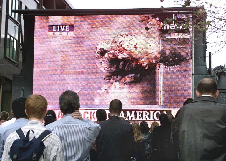 Trabajadores a la hora del almuerzo observan una pantalla gigante en Martin Place, Sídney, el 12 de septiembre de 2001, que muestra imágenes gráficas de las Torres Gemelas del World Trade Center de Nueva York tras ser impactadas por dos aviones.