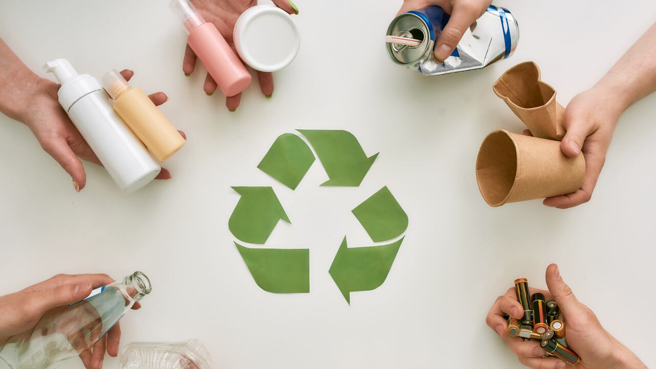 Vista superior de muchas manos sosteniendo diferentes tipos de residuos, basura con signo de reciclaje de papel en el centro sobre fondo blanco. Clasificación, concepto de reciclaje de residuos. Disparo horizontal. Vista superior.