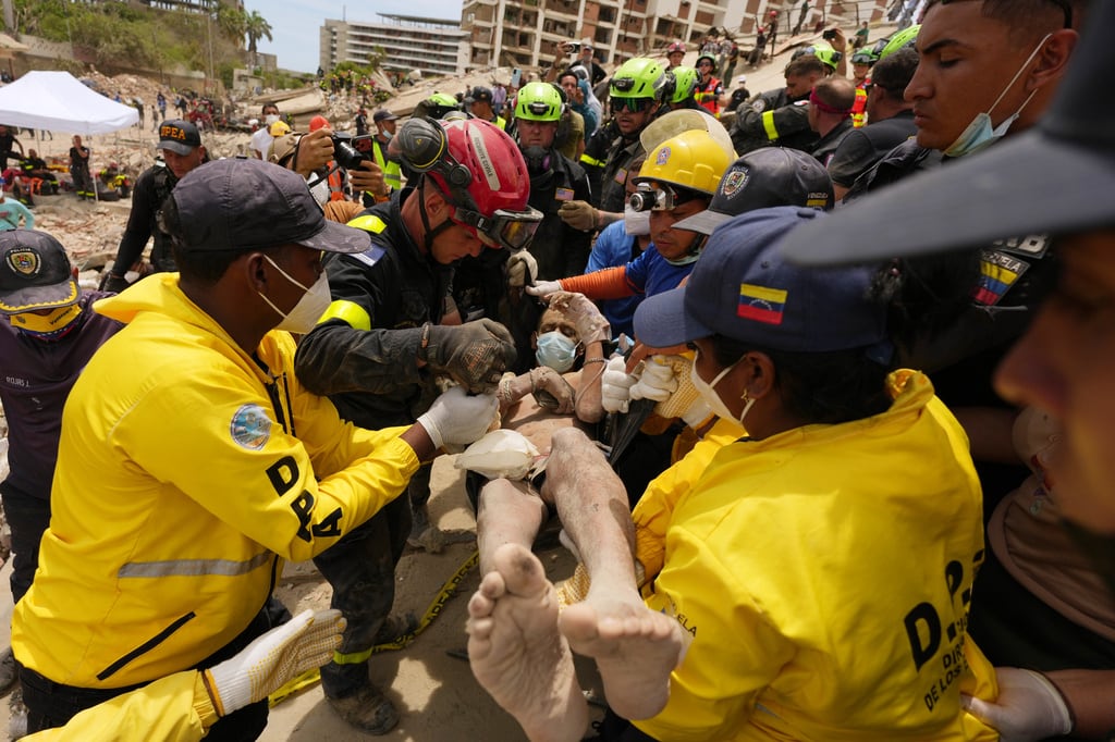 Trabajadores de rescate transportan a un hombre rescatado de un edificio que se derrumbó durante los terremotos que azotaron La Guaira, Venezuela.