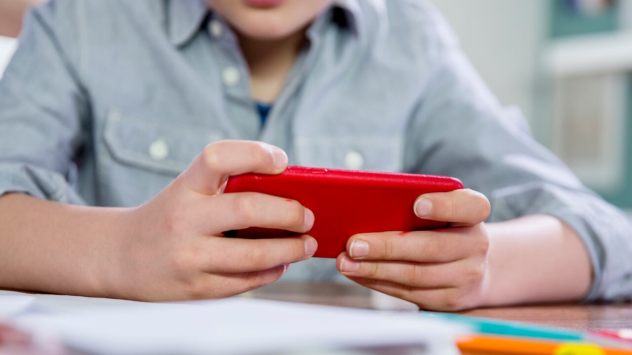 Niño de 10 años jugando con un teléfono inteligente en la escuela.