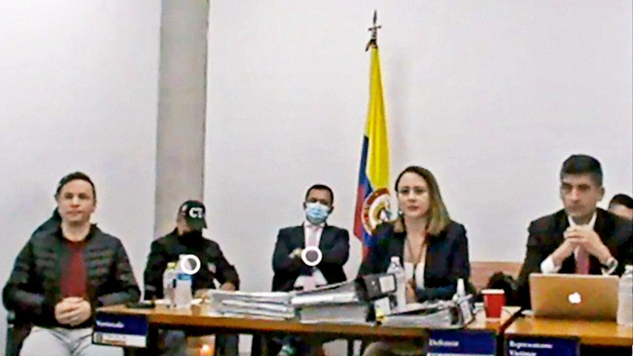 La mesa en la que se encontraban los fiscales, apenas a unos centímetros de Jhonier, estaba llena de documentos: las pruebas en su contra. Carpetas repletas de imágenes, transcripciones de llamadas, hojas con rótulos de Medicina Legal y de la Fiscalía e informes forenses.