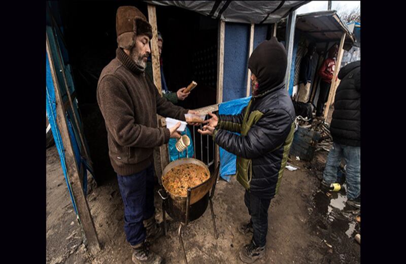 Un trabajador humanitario le entrega comida a uno de los más de 4.500 refugiados de Calais. Foto: Philippe Huguen / AFP