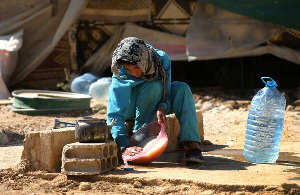 Una niña lava arroz afuera de su tienda de acampar, en los límites entre Siria y el Líbano, donde se refugia mientras pasa la guerra civil de su país. (AP)