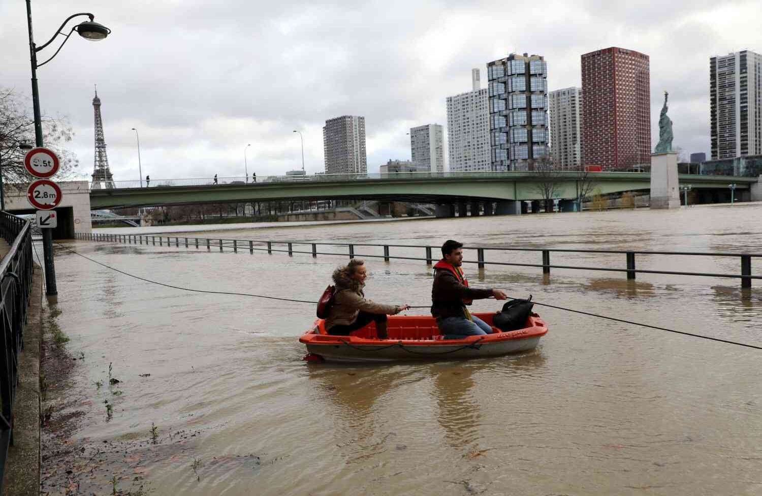 La gente usa un bote para acceder a una casa flotante después de que el río Sena se desbordó en París el 24 de enero de 2018. / AFP PHOTO / Ludovic Marin.