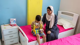 La abuela de Hind Rajab, una niña palestina de cinco años que quedó atrapada en un coche con miembros de su familia tras ser asesinados en enero de 2024 y que había pedido ayuda a los rescatadores antes de que se perdiera la comunicación con ellos, aparece sentada junto a su nieto, Iyad, hermano de Hind. Foto: Omar AL-QATTAA / AFP