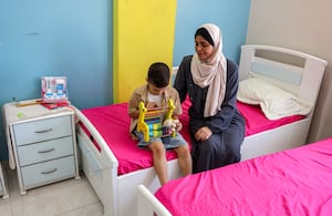 La abuela de Hind Rajab, una niña palestina de cinco años que quedó atrapada en un coche con miembros de su familia tras ser asesinados en enero de 2024 y que había pedido ayuda a los rescatadores antes de que se perdiera la comunicación con ellos, aparece sentada junto a su nieto, Iyad, hermano de Hind. Foto: Omar AL-QATTAA / AFP