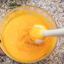 Young woman preparing pumpkin soup at home