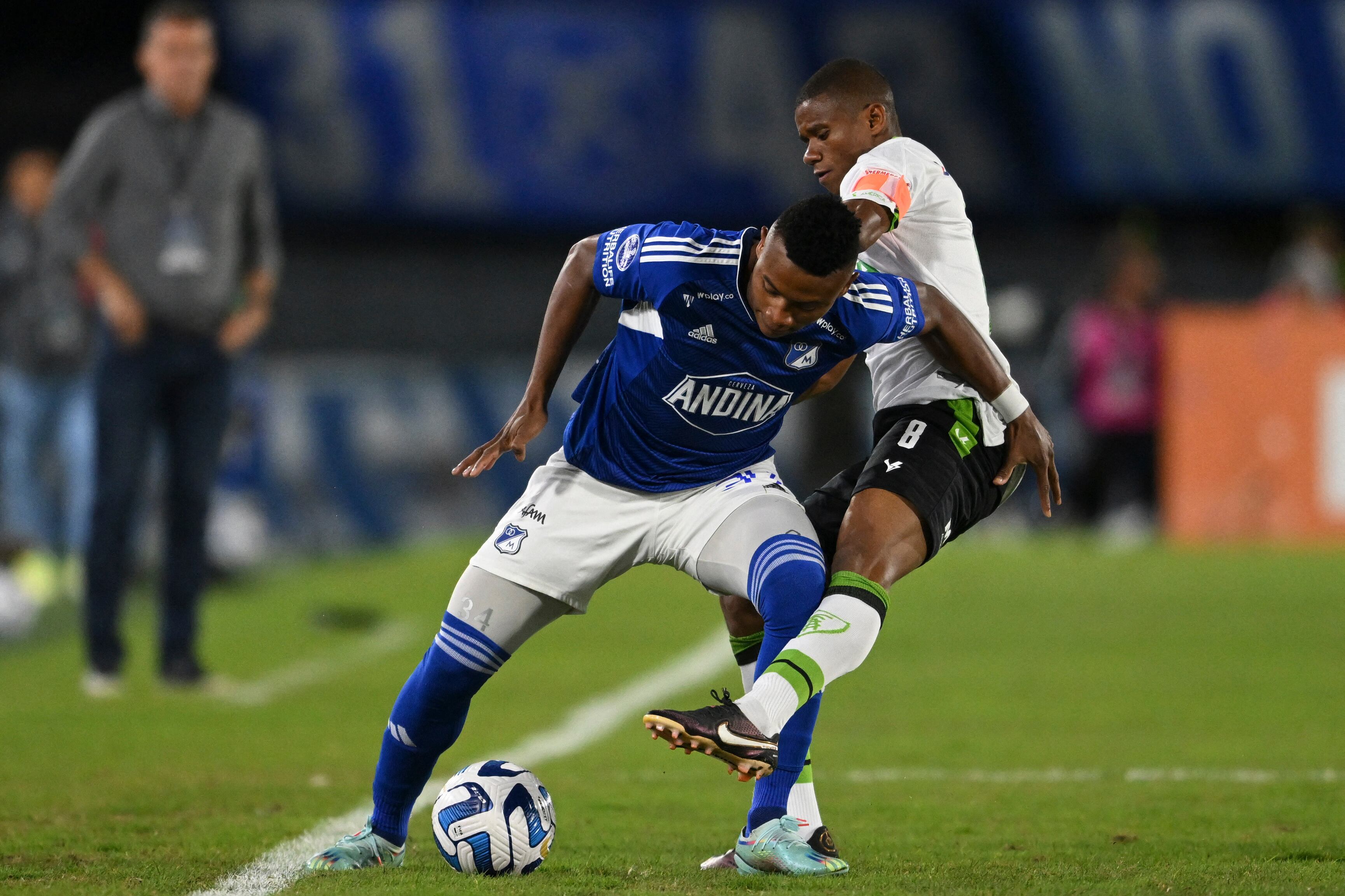 Millonarios' midfielder Oscar Cortes (L) and America MG's midfielder Juninho vie for the ball during the Copa Sudamericana group stage first leg football match between Colombia's Millonarios and Brazil's America Mineiro, at El Campin stadium in Bogota, on May 3, 2023. (Photo by Raul ARBOLEDA / AFP