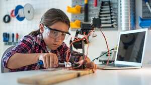 Young girl working in a robotics workshop.