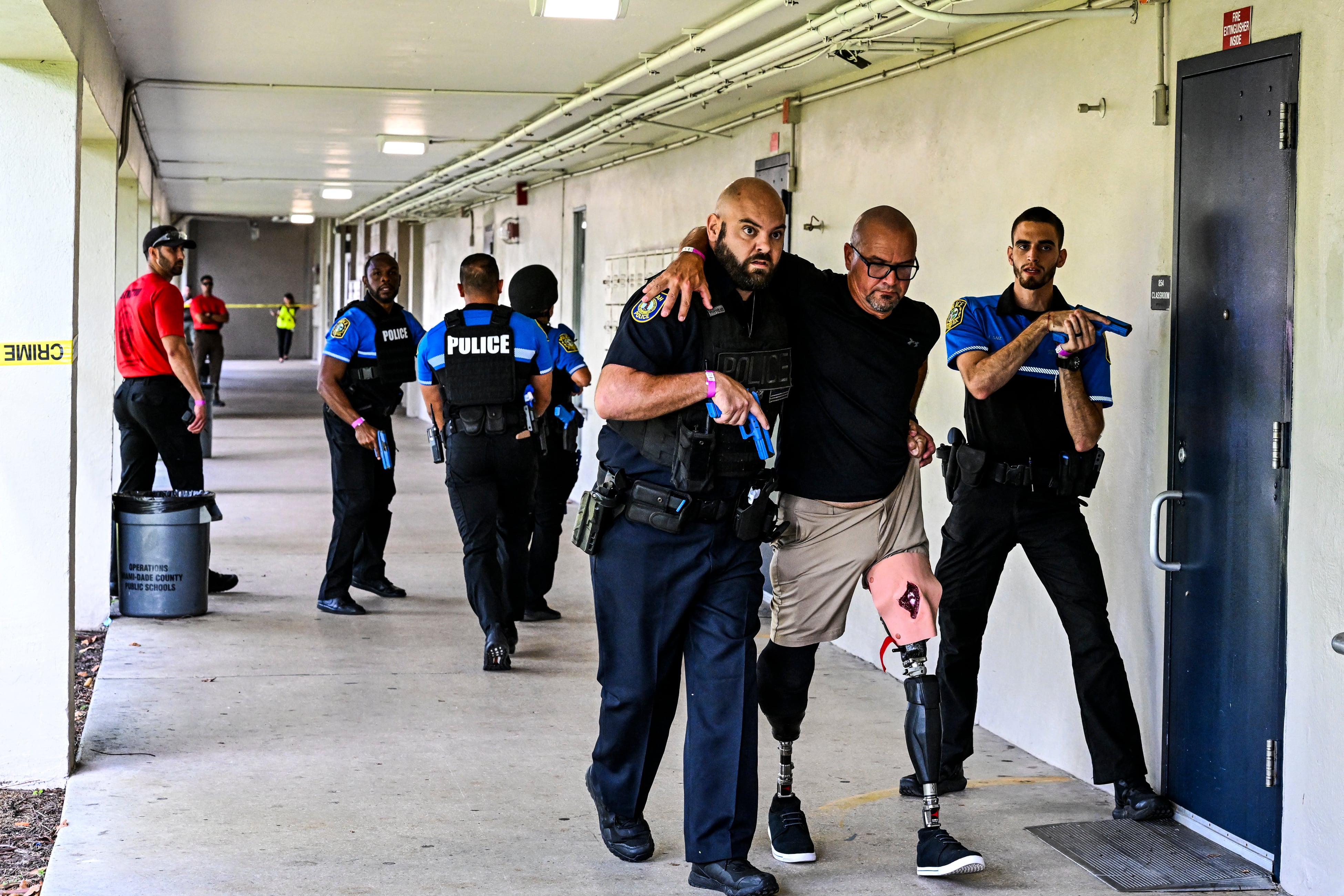 Un hombre se hace pasar por una víctima mientras los oficiales de policía de las escuelas de Miami-Dade realizan una operación de rescate mientras participan en un simulacro de tirador activo funcional a gran escala en la escuela secundaria Hialeah Senior High School en Hialeah, Florida, el 3 de agosto de 2022. (Foto de CHANDAN KHANNA / AFP)
