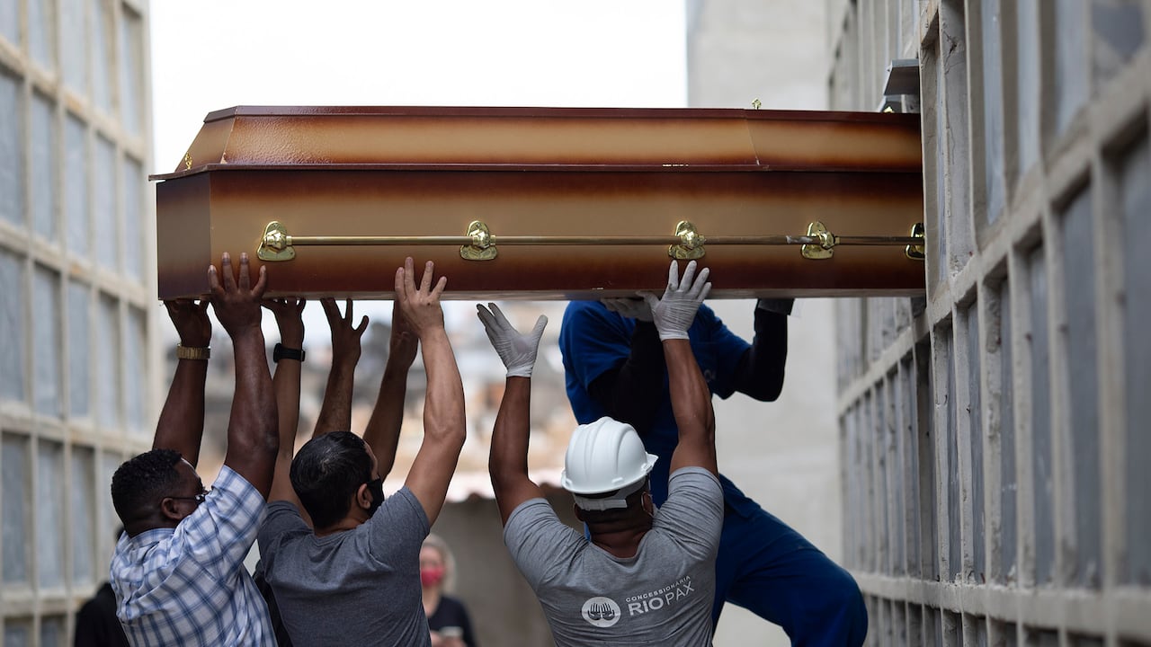 Los restos de una mujer que murió por complicaciones relacionadas con el COVID-19 son colocados en un nicho por trabajadores del cementerio y familiares en el cementerio de Inahuma en Río de Janeiro, Brasil. (Foto AP / Silvia Izquierdo)