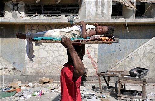 Un hombre lleva a una niña herida a la clínica Rue Petion en Puerto Príncipe.