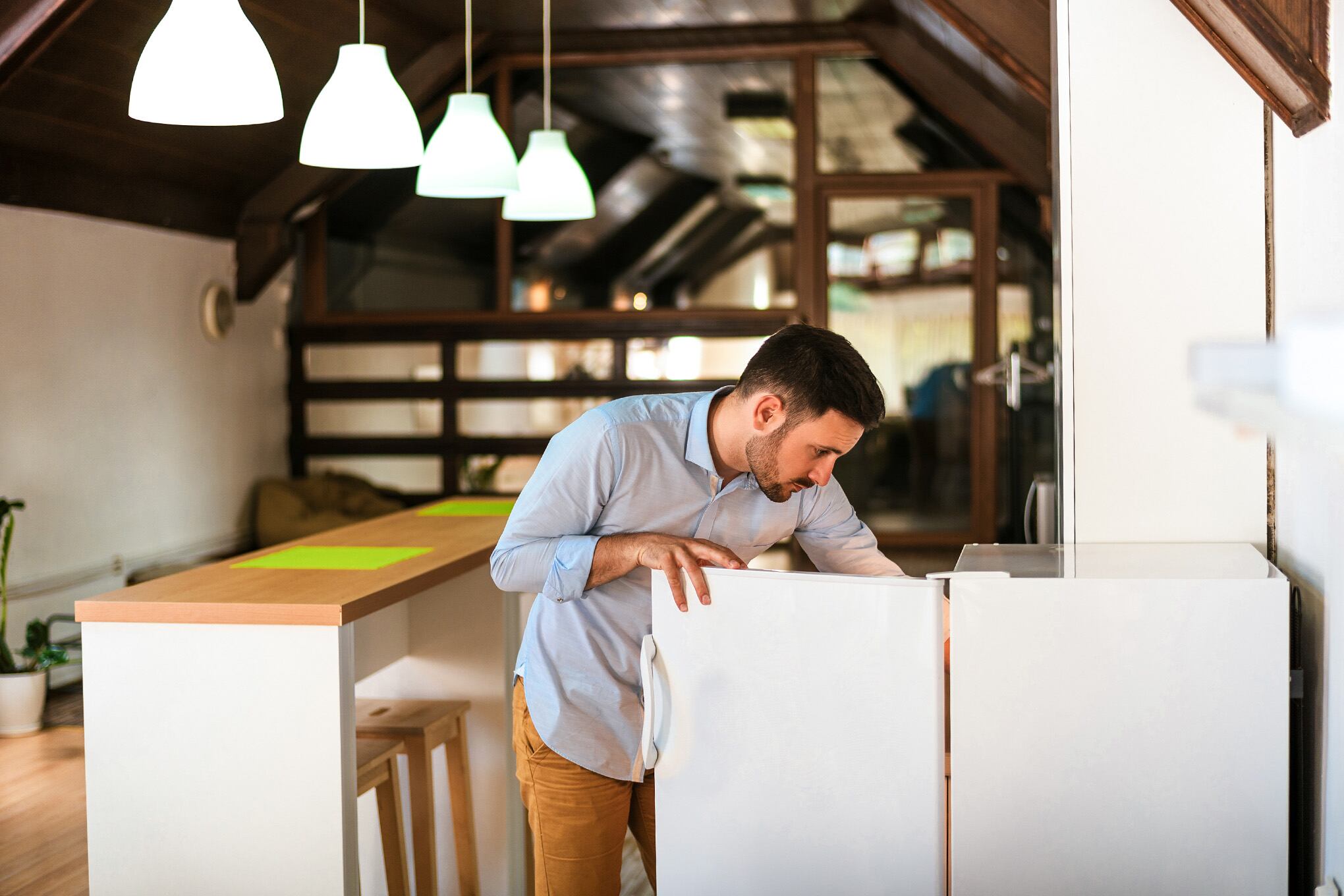 Puerta abierta nevera del hombre en la cocina en casa