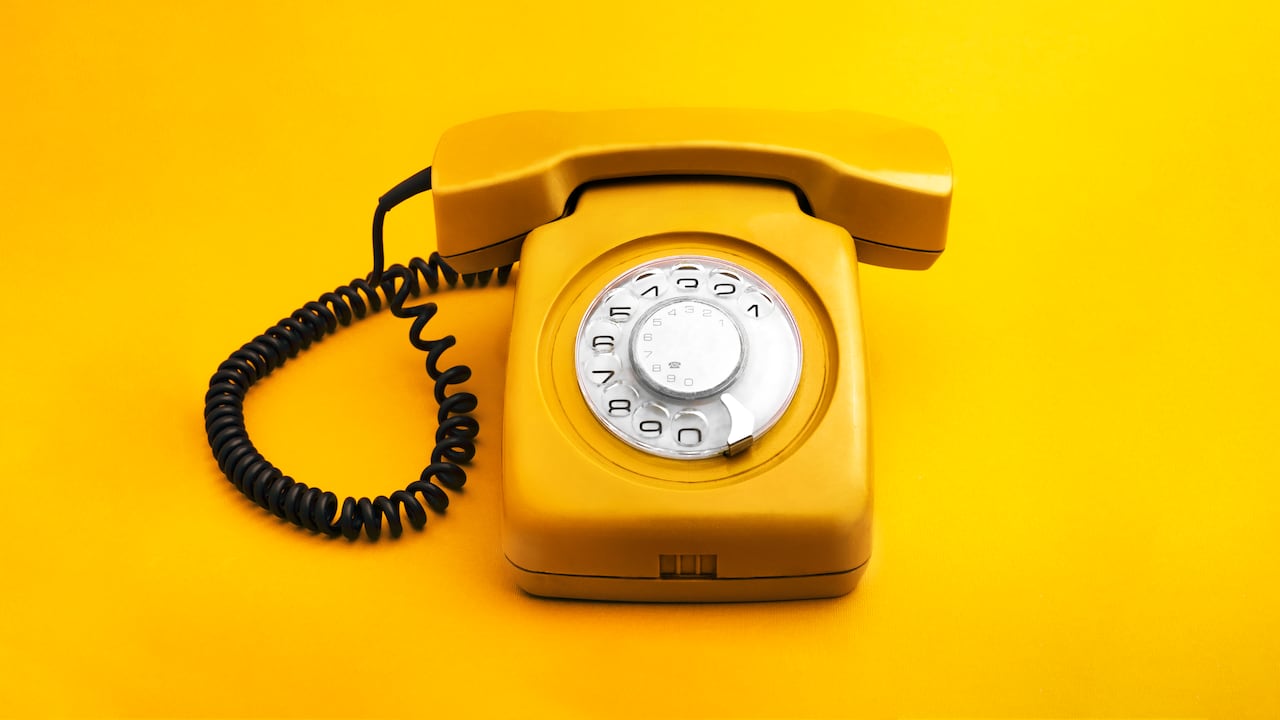 Teléfono amarillo retro sobre fondo amarillo.