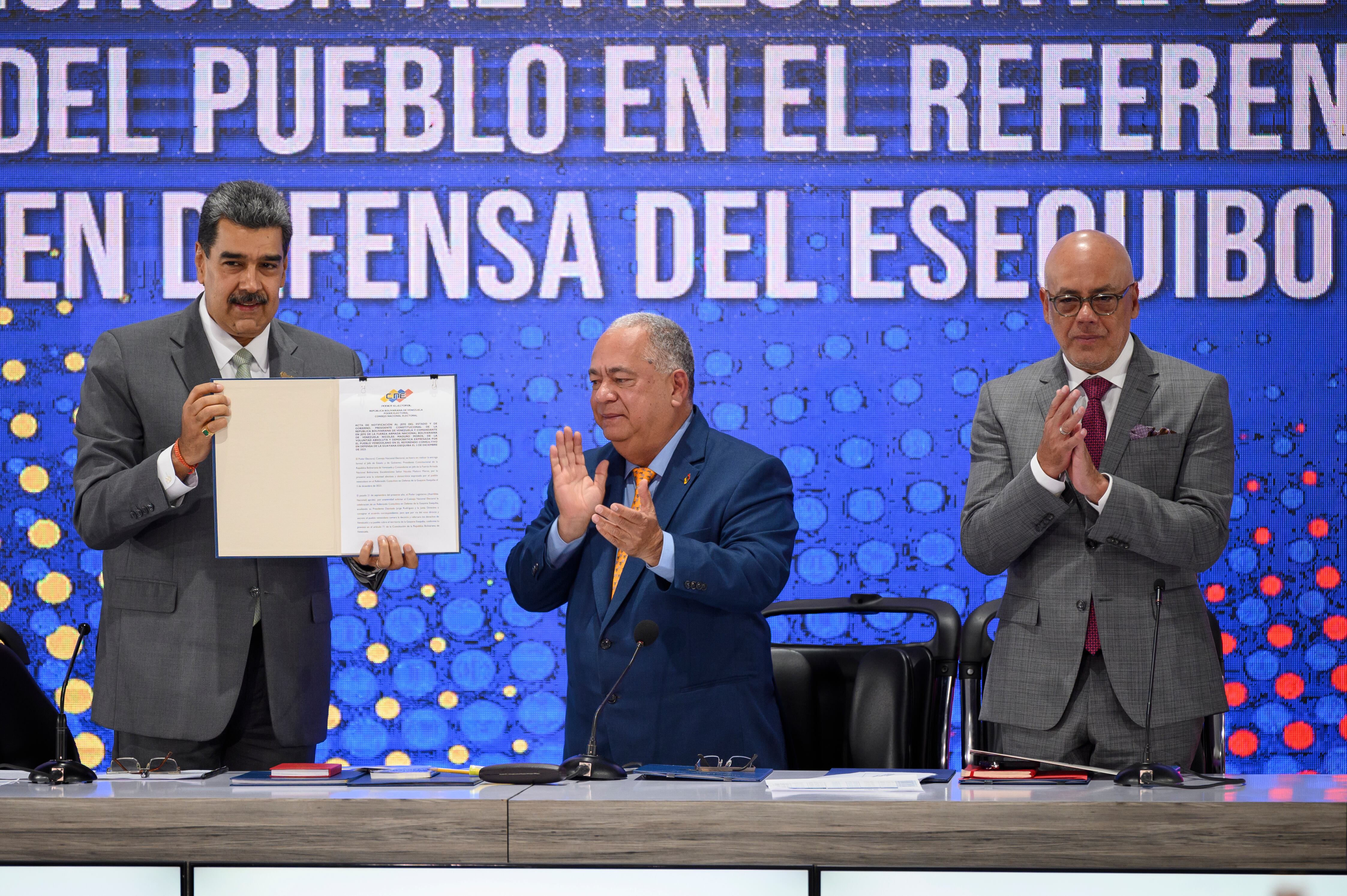 El Presidente de Venezuela, Nicolás Maduro, el Rector del Consejo Nacional Electoral, Elvis Amoroso, y el Presidente de la Asamblea Nacional, Jorge Rodríguez, muestran el acta de notificación del referéndum durante una conferencia de prensa el día después de que los venezolanos votaron en el referéndum sobre el conflicto fronterizo con el país vecino Guyana sobre la potencial región del Esequibo, rica en petróleo, el 4 de diciembre de 2023 en Caracas, Venezuela.