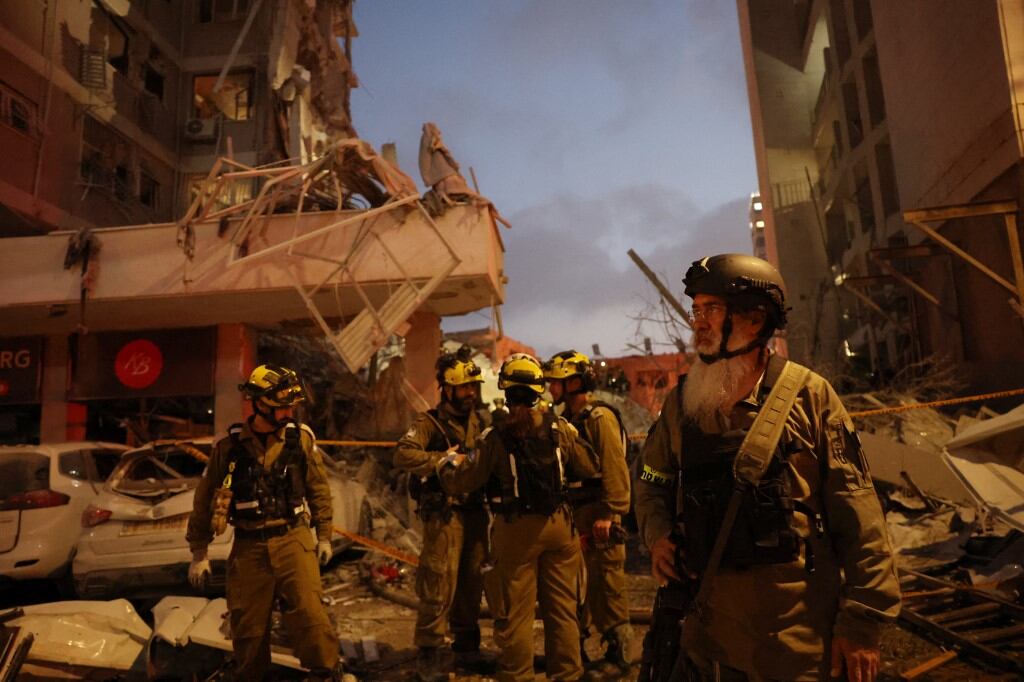 Los socorristas trabajan junto a un edificio dañado tras el ataque de un misil iraní en la ciudad israelí de Bat Yam, al sur de Tel Aviv, la madrugada del 15 de junio de 2025. Las sirenas y explosiones antiaéreas sonaron en Jerusalén y Tel Aviv la madrugada del 15 de junio, informaron periodistas de la AFP, mientras Israel e Irán intercambiaban disparos por tercer día consecutivo. (Photo by Jack GUEZ / AFP)