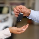 Close-up on a salesman giving the keys to their new car to a happy couple at the dealership - car ownership concepts