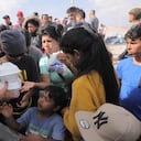 Migrantes venezolanos reciben alimentos mientras esperan información para ingresar a Perú en Arica, en la frontera entre Chile y Perú. (Foto de AGUSTÍN MERCADO / AFP)
