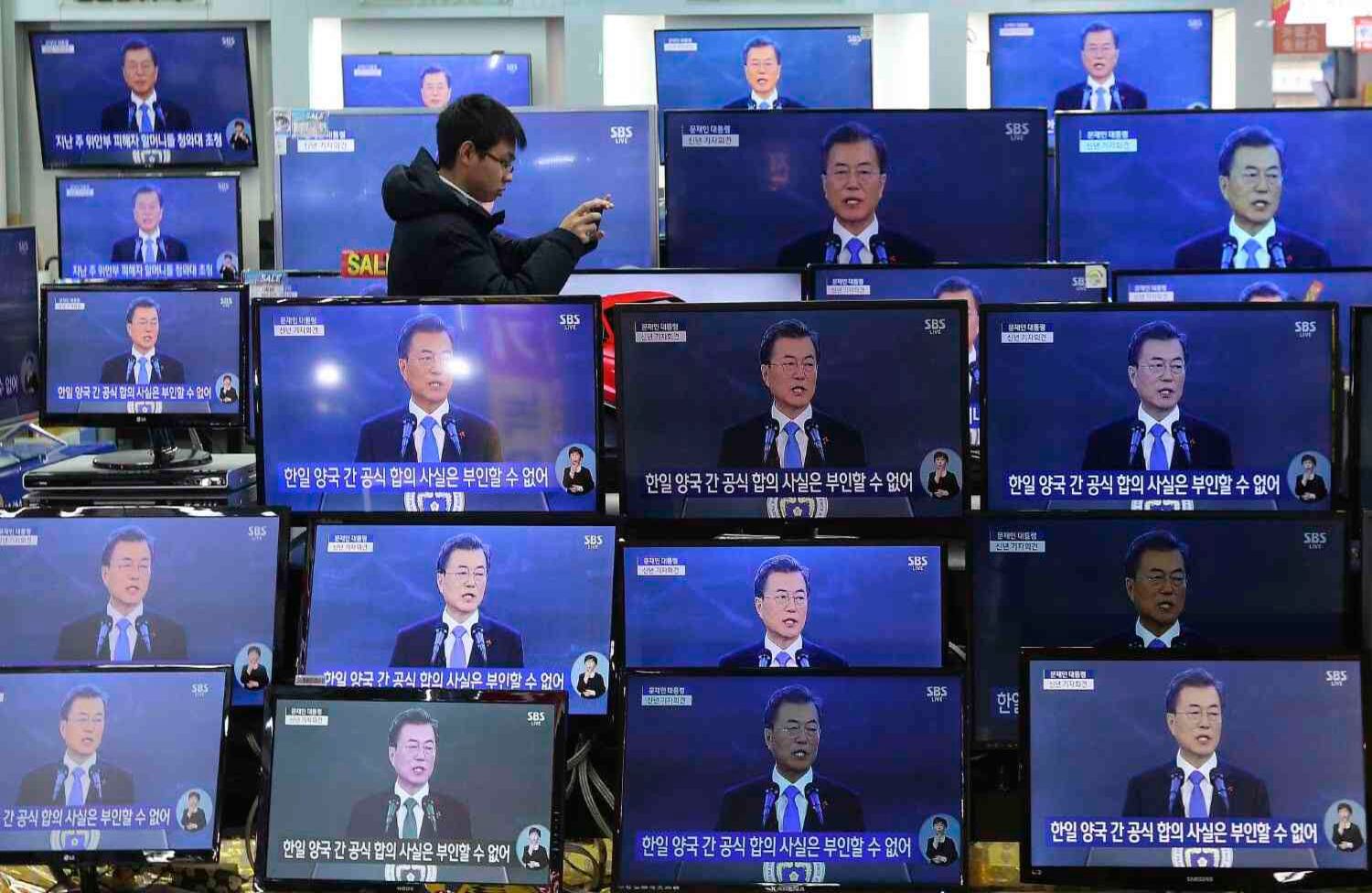 Un hombre toma fotografías junto a las pantallas de televisión que muestran la transmisión en vivo del discurso de Año Nuevo del presidente surcoreano Moon Jae-in en la tienda Yongsan Electronic en Seúl, Corea del Sur. Moon dijo que impulsará más conversaciones y cooperación con Corea del Norte para resolver el problema nuclear. (AP Photo / Ahn Young-joon, archivo)