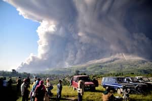 La gente observa cómo el monte Sinabung arroja material volcánico durante una erupción en Karo, en el norte de Sumatra, Indonesia, el martes 2 de marzo de 2021. El volcán de 2.600 metros (8.530 pies) entró en erupción el martes, enviando materiales volcánicos a unos pocos miles de metros al cielo depositando cenizas en las aldeas cercanas. (Foto AP)