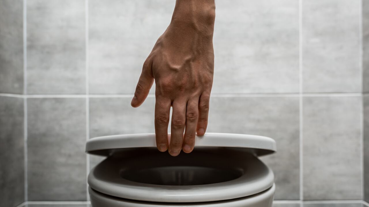 Vista recortada del hombre sosteniendo la tapa del inodoro en un baño moderno - Imagen de referencia