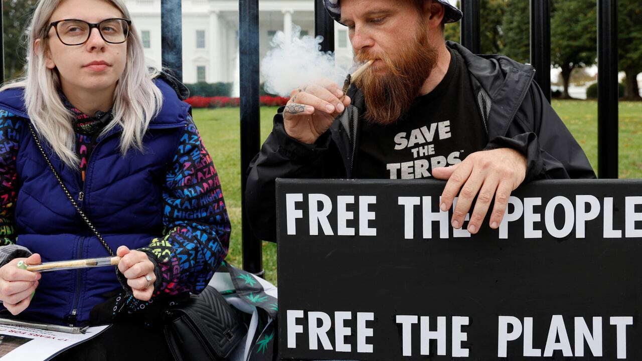 Los manifestantes Audrey Rotunda y Joseph Accettullo, de la New England Craft Cannibis Alliance, fuman a las puertas de la Casa Blanca durante una concentración en la que se insta al presidente de Estados Unidos, Joe Biden, a liberar a todos los presos condenados por cargos relacionados con la marihuana, a las puertas de la Casa Blanca en Washington, Estados Unidos, el 24 de octubre de 2022. REUTERS/Jonathan Ernst