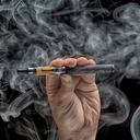 Mano sosteniendo un cigarrillo electrónico sobre un fondo oscuro