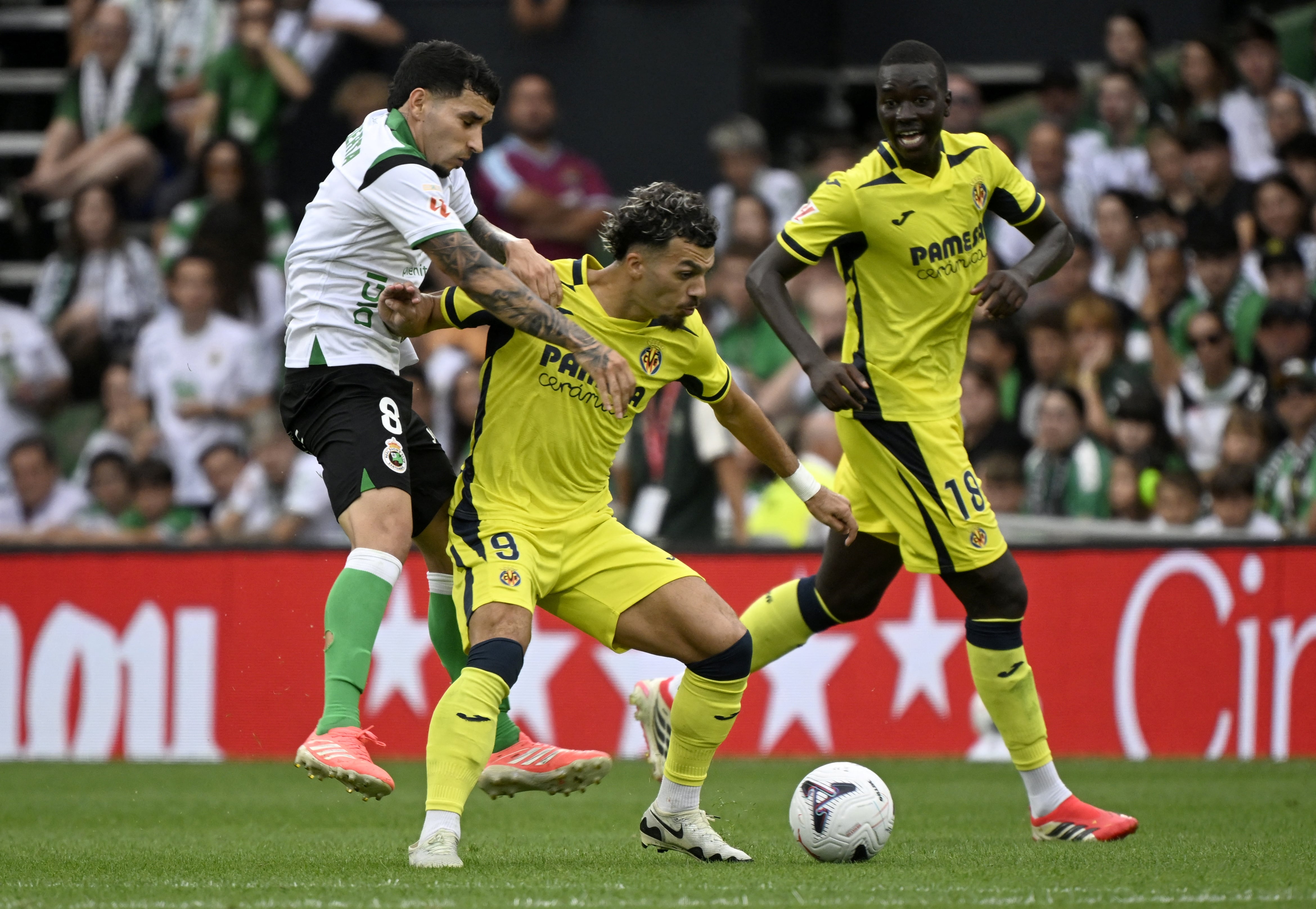 Villarreal's Georgian forward #09 Georges Mikautadze (C) fights for the ball with Racing Santander's Colombian midfielder #08 Gustavo Puerta during the Spanish league football match between Racing Santander and Villarreal in El Sardinero stadium in Santander on August 16, 2026. (Photo by ANDER GILLENEA / AFP)