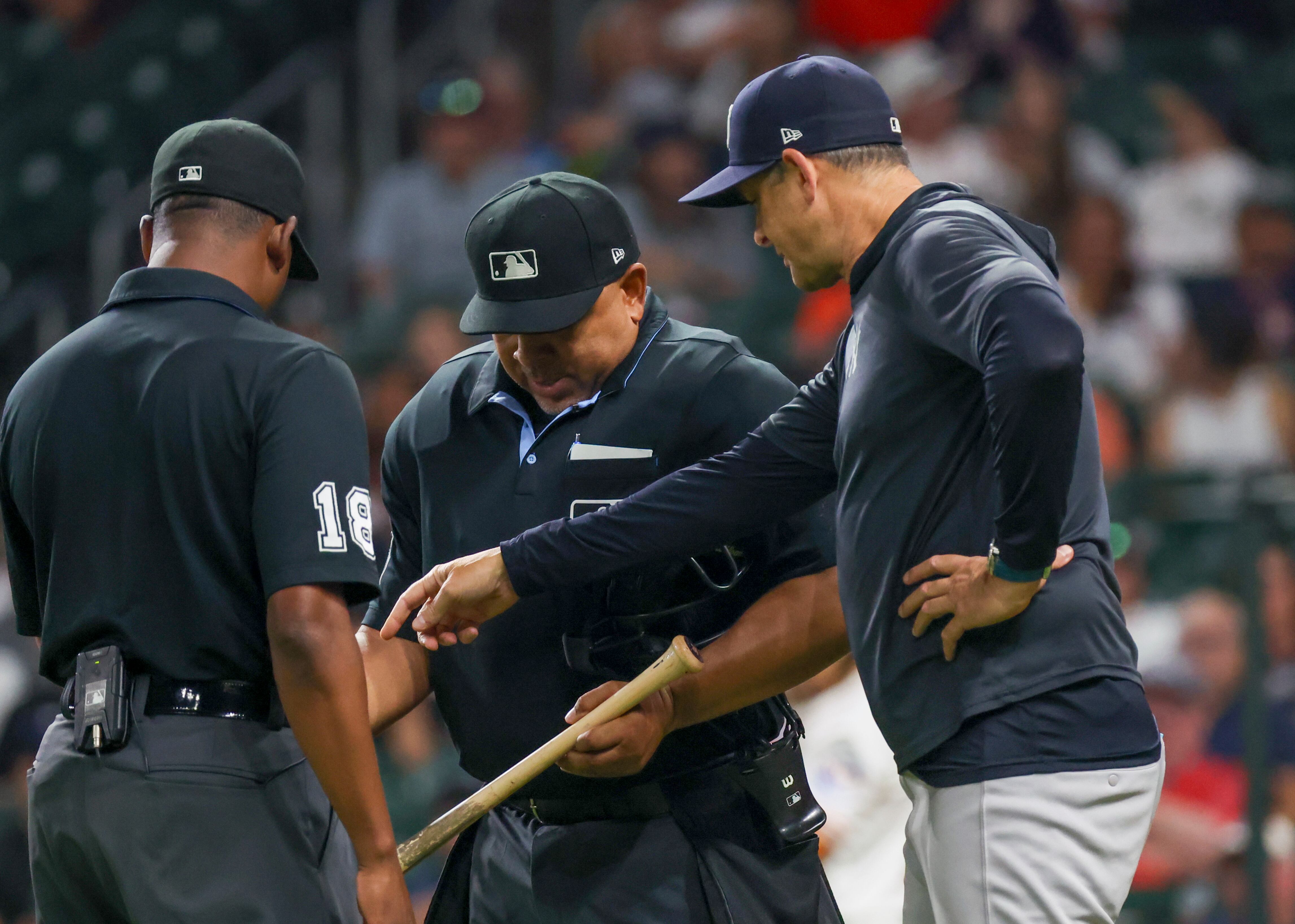 HOUSTON, TX - SEPTEMBER 04: (left to right) second base umpire Ramon De Jesus (18), head umpire Adrian Johnson (80) and New York Yankees manager Aaron Boone (17) inspect the bat of Houston Astros outfielder Taylor Trammell (26) (not pictured) as it is suspected that the bat has been sanded during the MLB game between the New York Yankees and Houston Astros on September 4, 2025 at Daikin Park in Houston, Texas. (Photo by Leslie Plaza Johnson/Icon Sportswire via Getty Images)