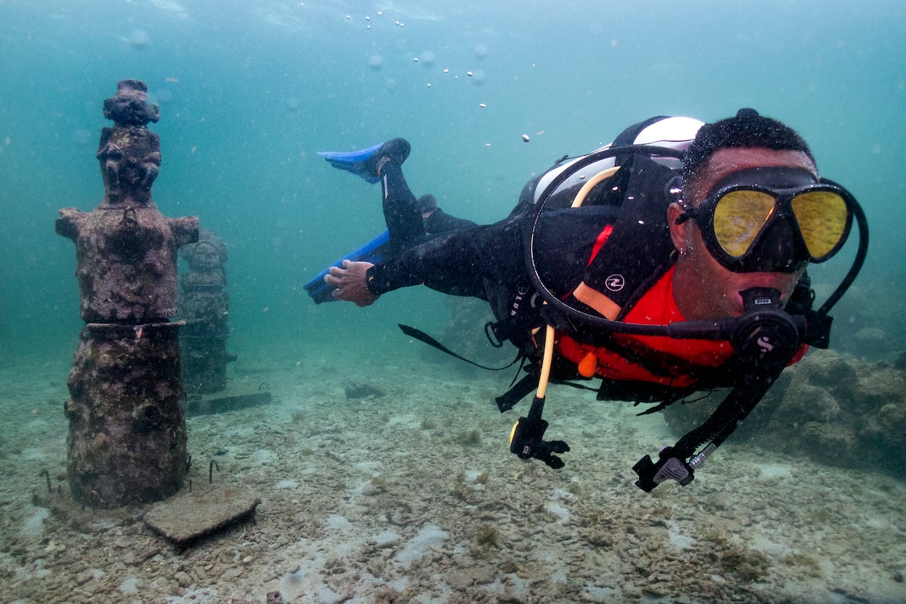 El guía Orlis Navas bucea en el MUSZIF underwater museum in Isla Fuerte, Bolivar department, Colombia, on May 22, 2024. In the Colombian Caribbean an underwater museum protects coral reefs threatened by tourism and climate change. (Photo by Luis ACOSTA / AFP)
