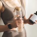 Mujer sosteniendo una botella de agua y una botella de vitaminas o proteínas. Concepto de estilo de vida saludable y deporte.