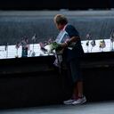 Una doliente coloca una bandera en la piscina sur antes de las ceremonias para conmemorar el vigésimo aniversario de los ataques terroristas del 11 de septiembre, el sábado 11 de septiembre de 2021, en el Museo y Memorial Nacional del 11 de septiembre en Nueva York. (Foto AP / John Minchillo)