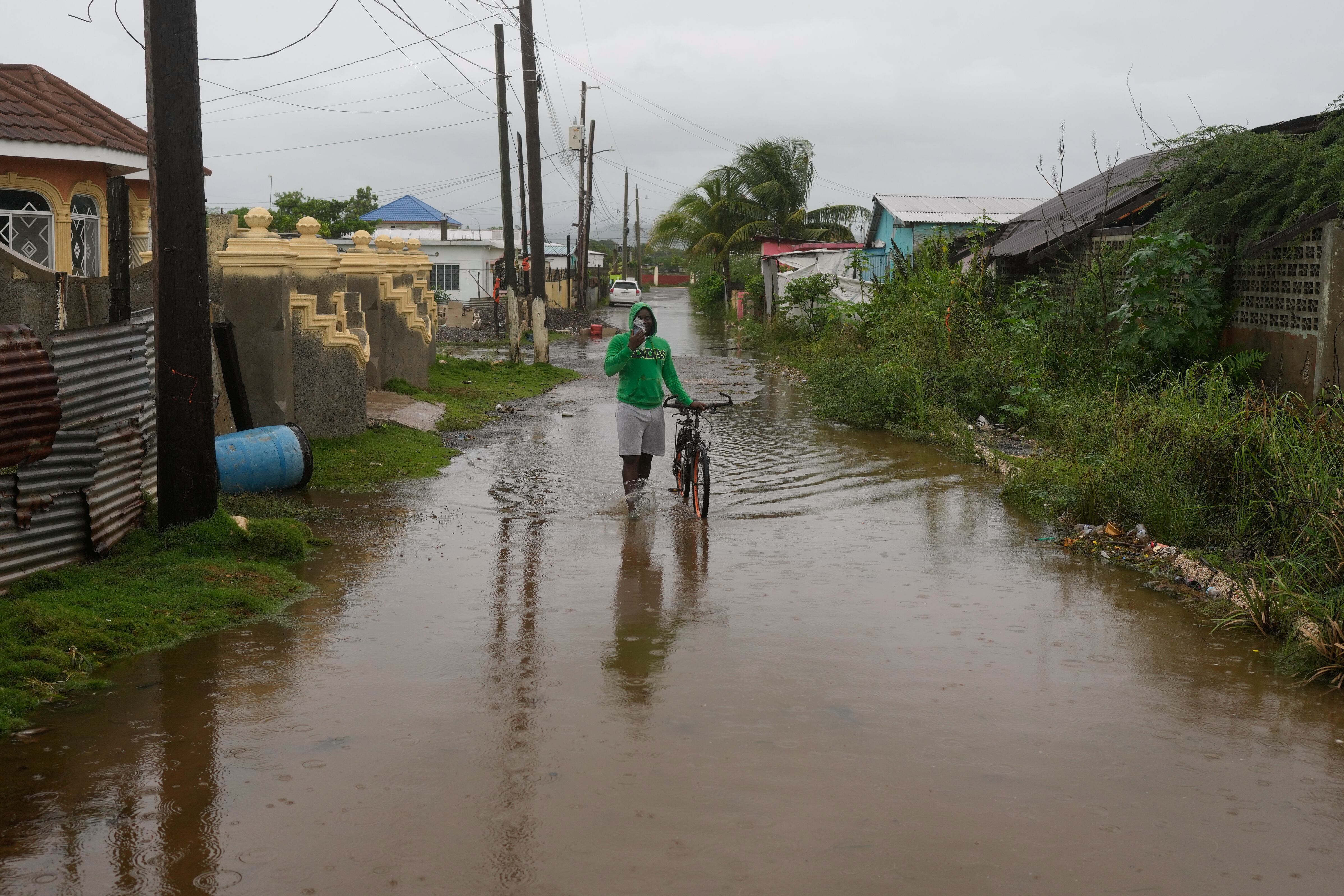 Un hombre camina por una calle inundada antes de la llegada del huracán Melissa, el lunes 27 de octubre de 2025, a Old Harbour, Jamaica.