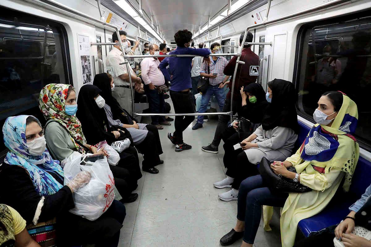 Las personas que usan tapabocas para ayudar a prevenir la propagación del coronavirus se sientan dentro de un tren en Teherán, Irán. (Foto AP / Ebrahim Noroozi)