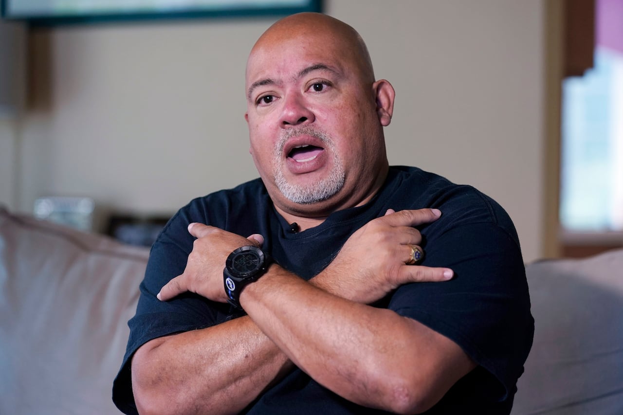 Will Jimeno, un ex agente de policía de la Autoridad Portuaria que fue rescatado de entre los escombros del World Trader Center el 11S, muestra como cruzó los brazos haciendo el signo de "Te quiero", durante una entrevista en su casa en Chester, Nueva Jersey, el 2 de agosto de 2021. Quería mandar un mensaje a su familia si moría entre los restos. (AP Foto/Richard Drew)