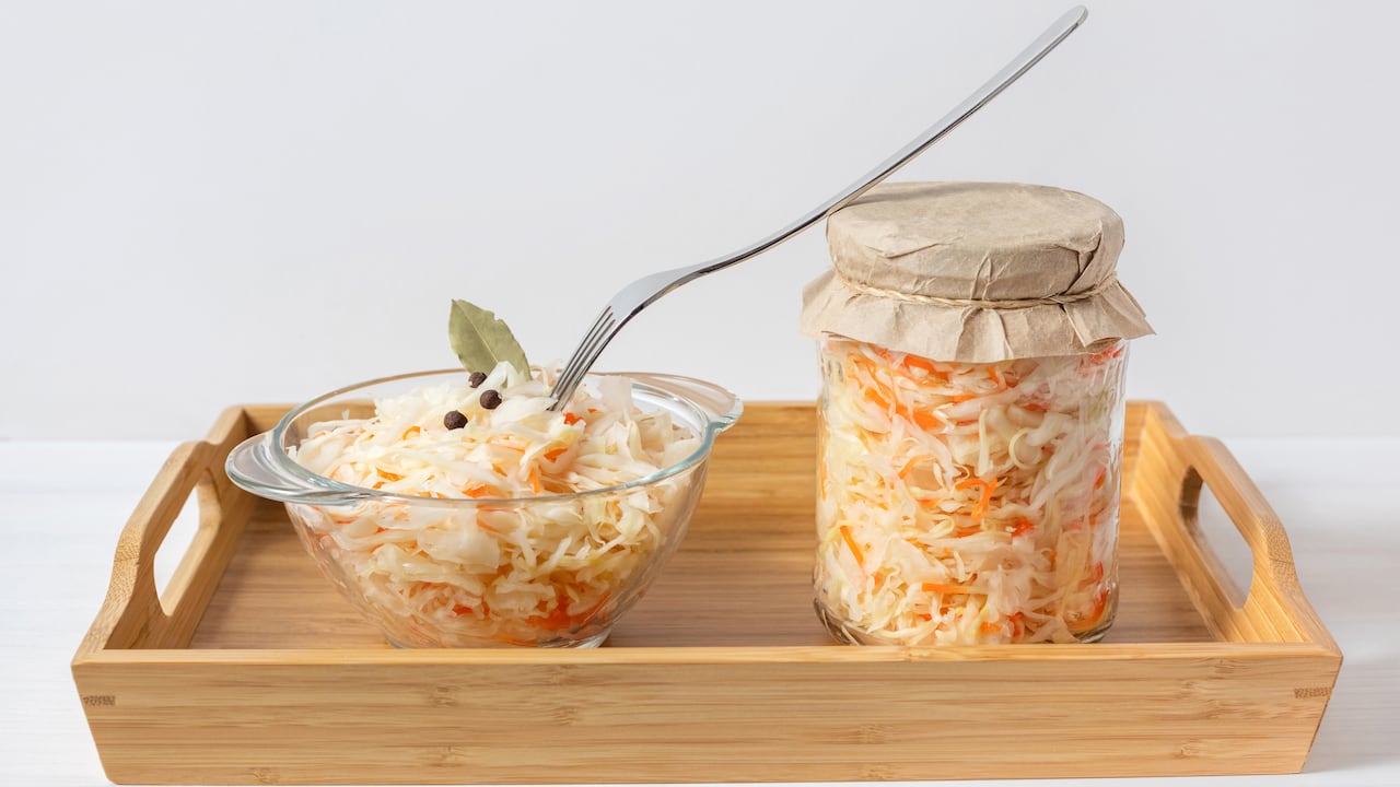 Chucrut en un frasco y un recipiente, mezclado con zanahorias. Comida fermentada.