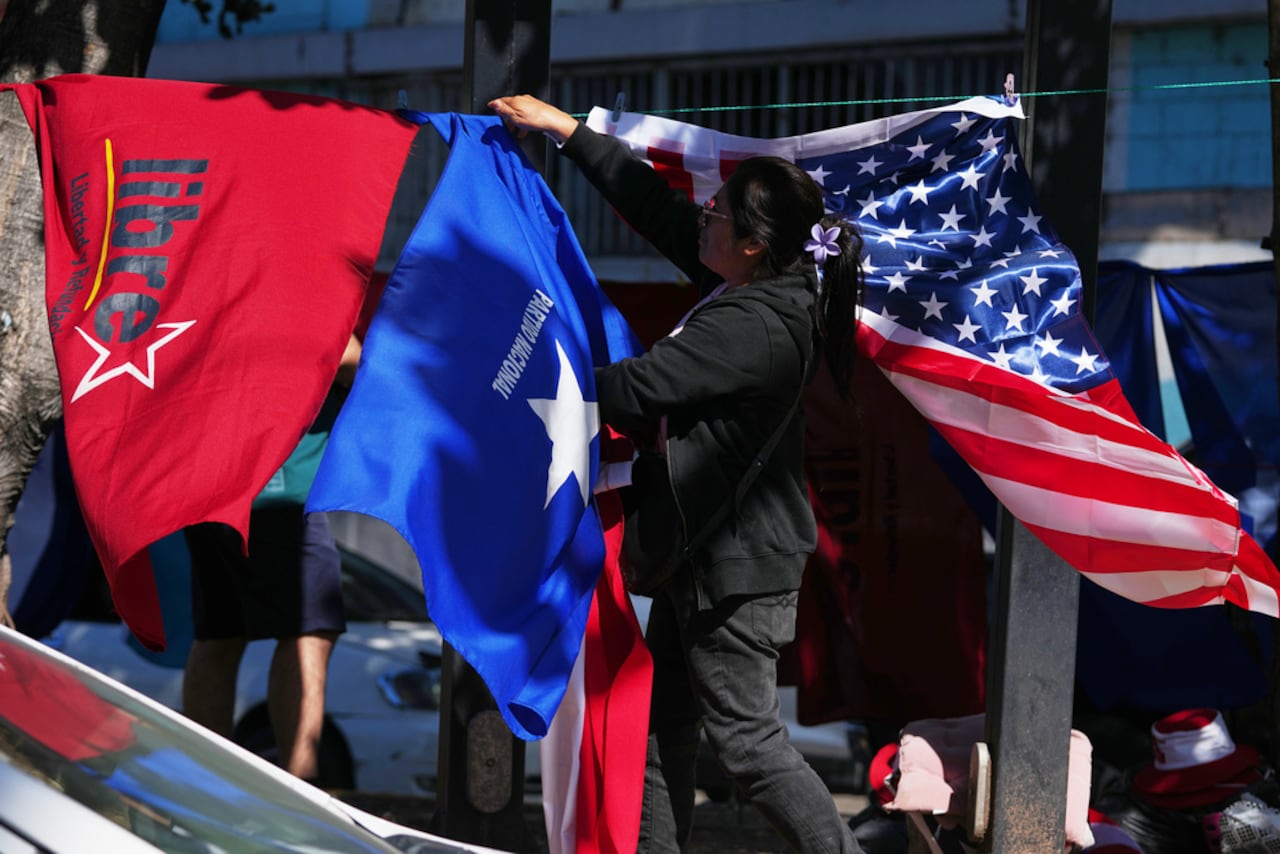 Un vendedor ambulante cuelga banderas que representan al Partido Nacional LIBRE (de izquierda a derecha), y a Estados Unidos, cerca del estadio nacional en Tegucigalpa, Honduras