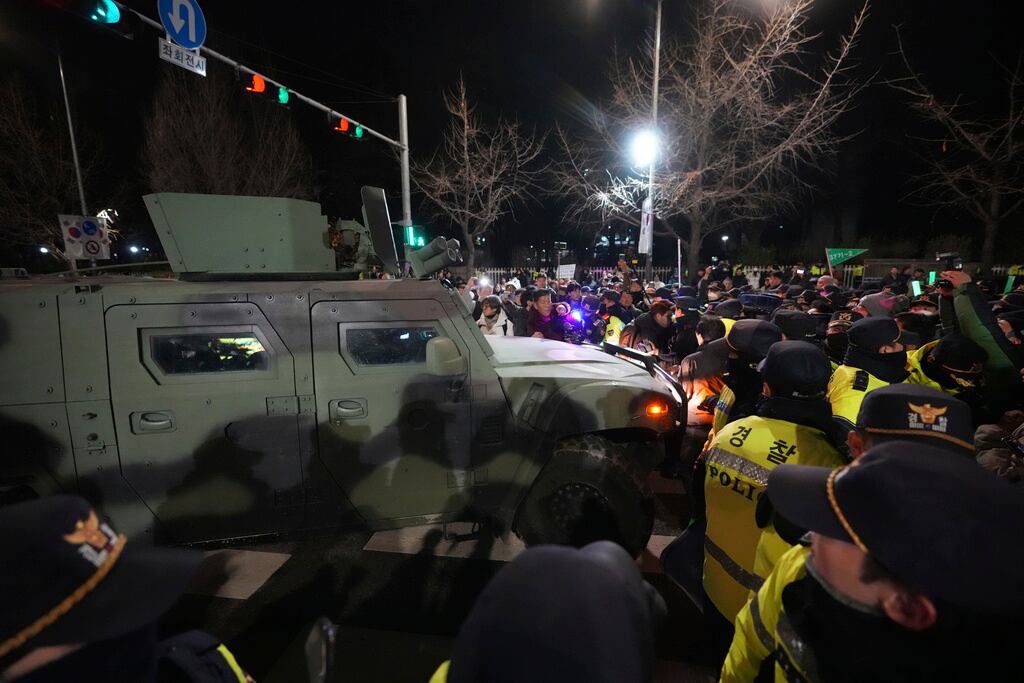 Un vehículo militar es escoltado por agentes de policía mientras la gente intenta bloquear el exterior de la Asamblea Nacional en Seúl, Corea del Sur, el miércoles 4 de diciembre de 2024. (Foto AP/Lee Jin-man)