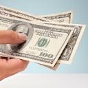 Mano sosteniendo una selección de billetes de dólar estadounidense