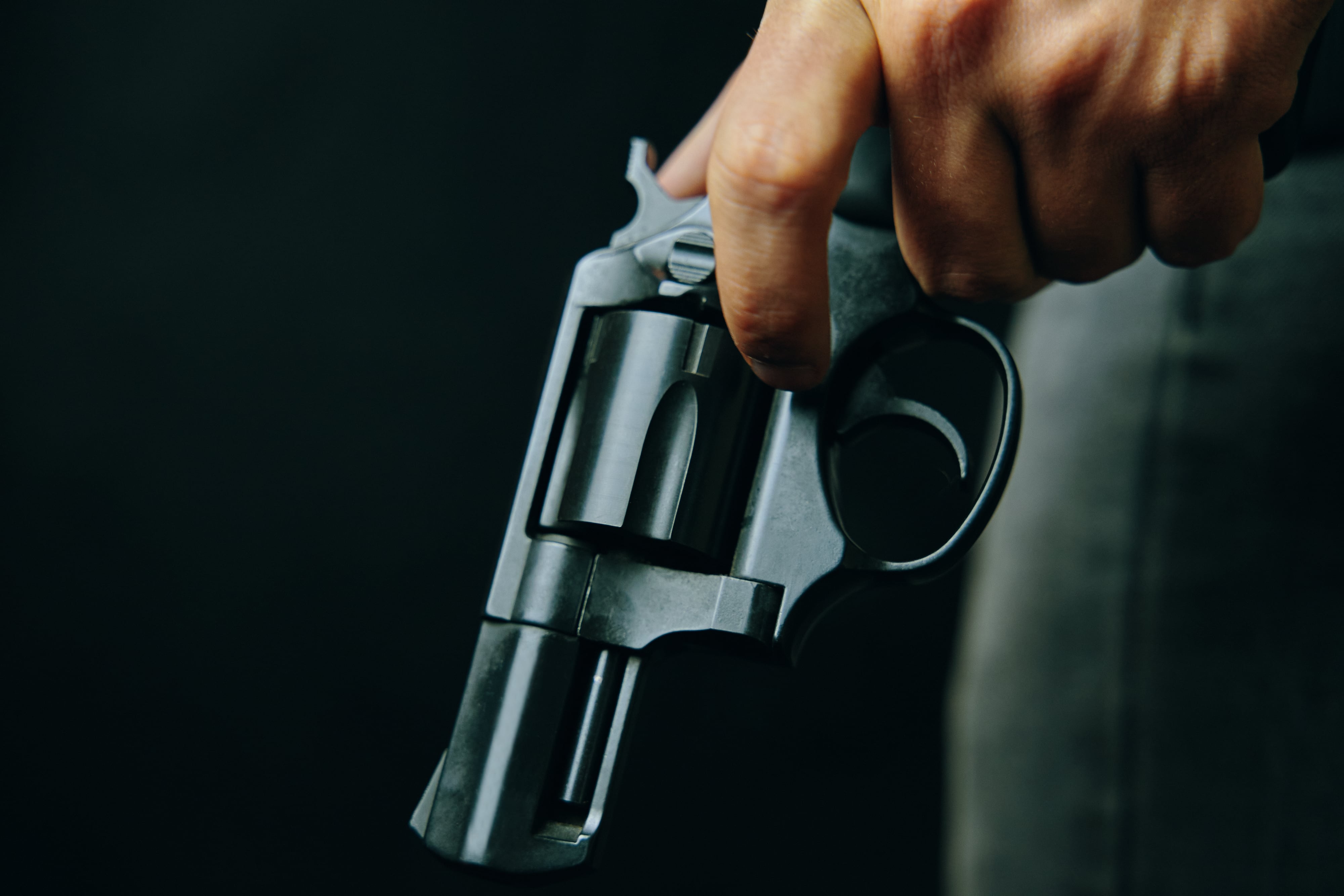 Criminal con revólver sobre fondo oscuro