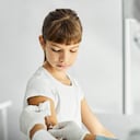 Doctora inyectando la vacuna Covid-19 en el brazo de la niña en la sala de examen médico. Trabajadora de la salud está trabajando en el hospital. Están en la clínica.