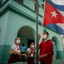 Los estudiantes que usan máscaras como medida de precaución en medio de la propagación del COVID-19 bajan la bandera cubana para que no se moje bajo la lluvia en su primer día de clases después de meses sin clases presenciales en La Habana, Cuba. Foto AP / Ramón Espinosa