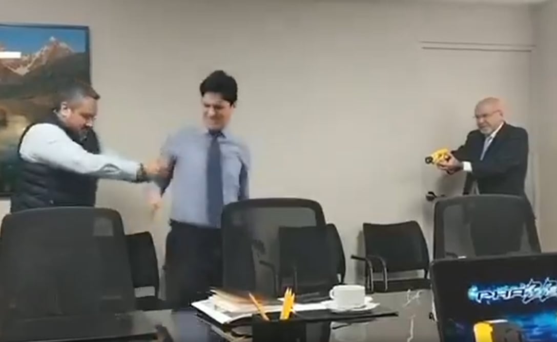 Carlos Bruce prueba su pistola eléctrica con un empleado del municipio.
