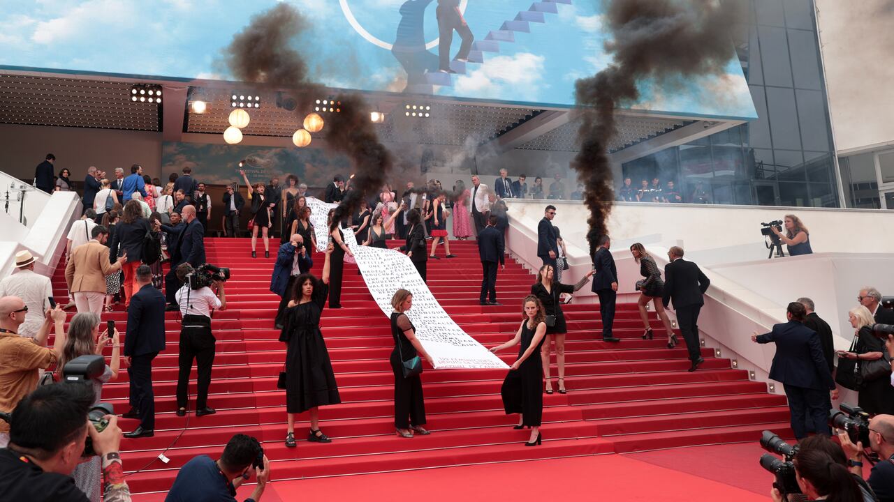 Miembros del movimiento feminista 'Les Colleuses' sostienen una pancarta que muestra los nombres de 129 mujeres que murieron como resultado de violencia doméstica antes de la proyección de "Holy Spider" durante el 75º festival anual de cine de Cannes en el Palais des Festivals.