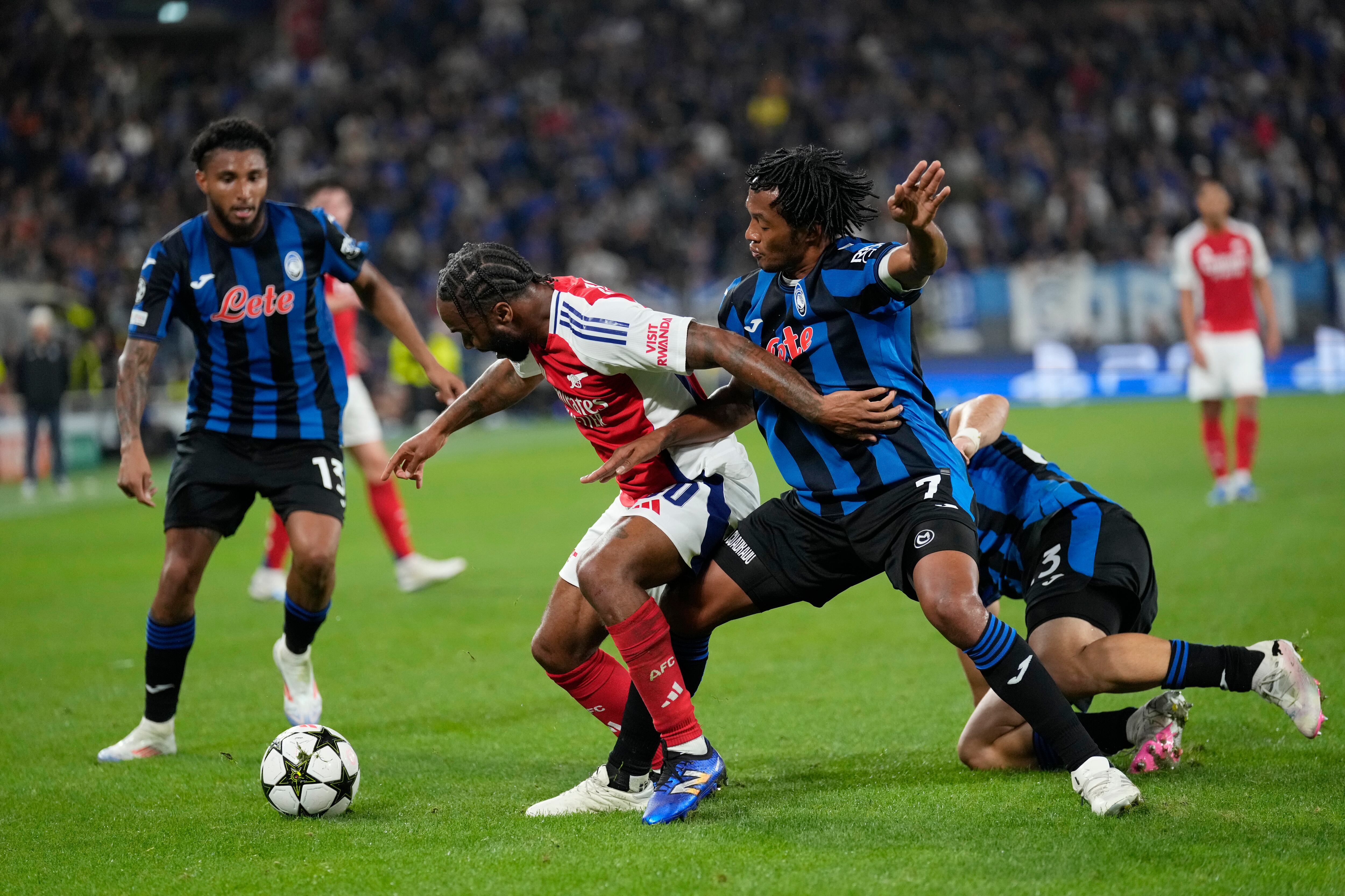 Arsenal's Raheem Sterling, centre left, and Atalanta's Juan Cuadrado challenge for the ball during the Champions League opening phase soccer match between Atalanta and Arsenal at the Bergamo's stadium in Bergamo, Italy, Thursday, Sept. 19, 2024. (AP Photo/Antonio Calanni)
